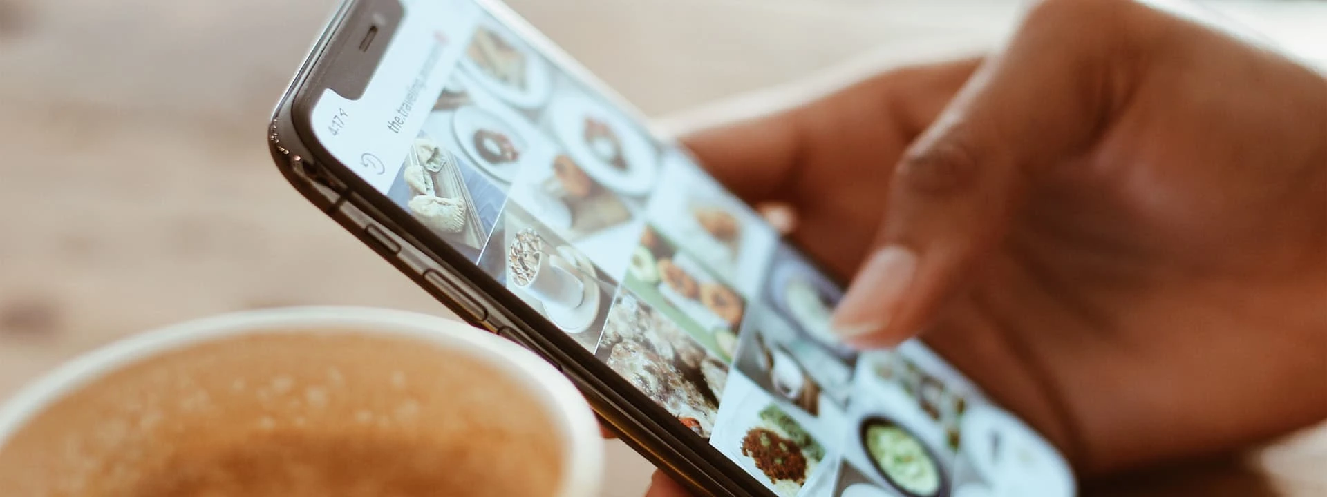 A person's hand holding a mobile phone while looking at a social media feed